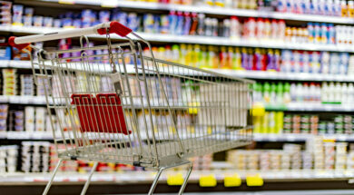 A shopping cart by a store shelf in a supermarket