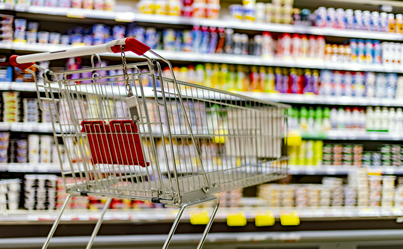 A shopping cart by a store shelf in a supermarket