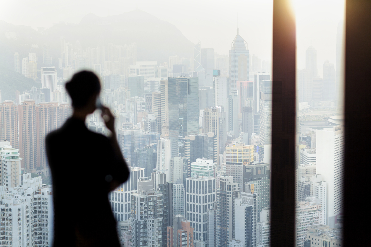 Man looking through window at cityscape stock photo - OFFSET