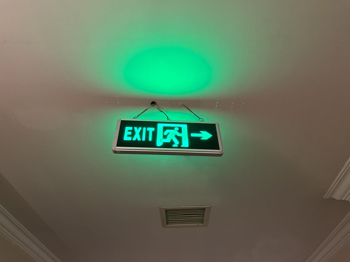 Promoting Safety and Security: Clear Green Emergency Exit Sign for Quick Evacuation in Hotel Building Corridor