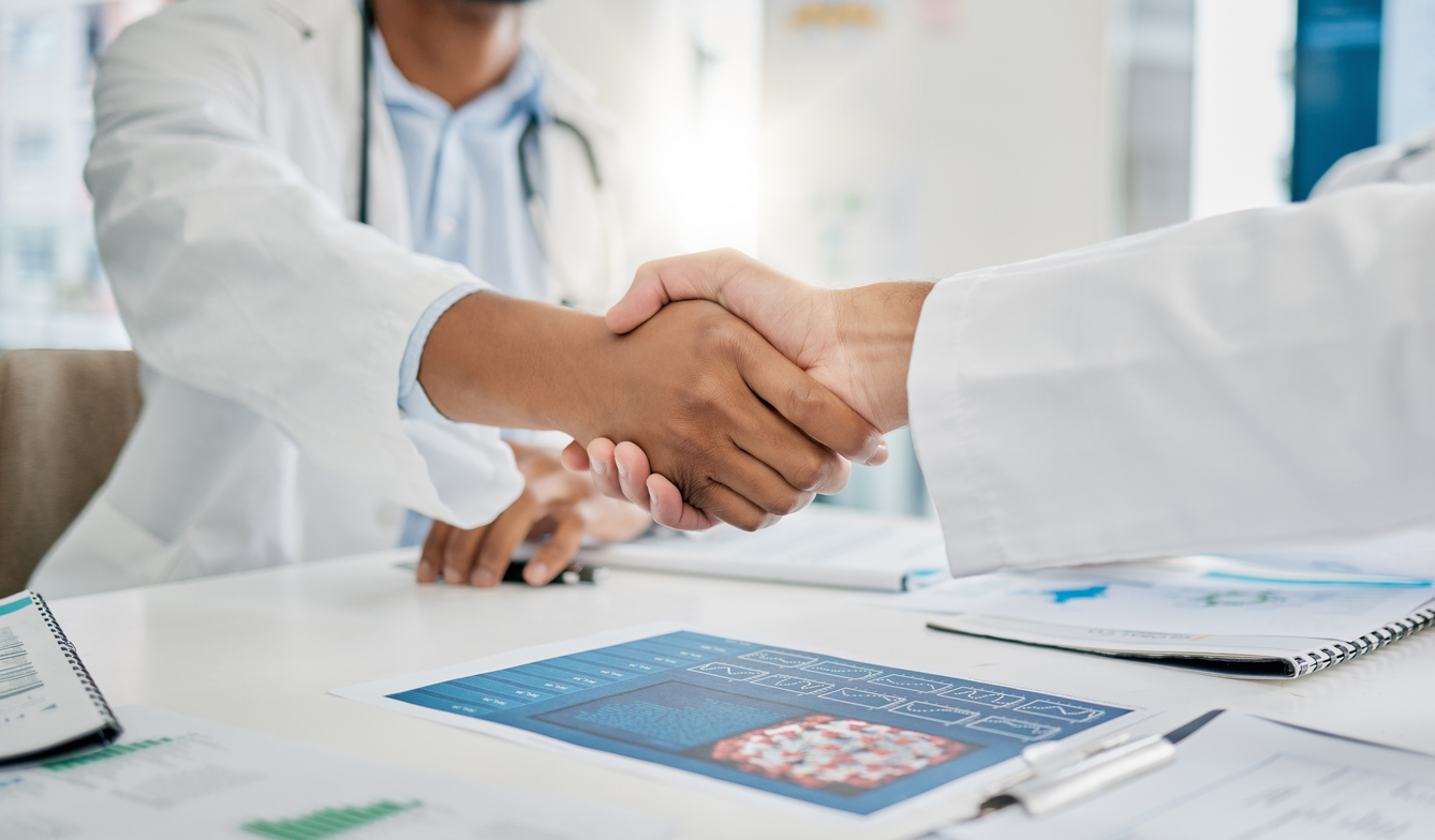 Closeup handshake, doctors and agreement for documents, research or health in hospital to stop virus. Doctor, shaking hands and motivation for healthcare service, wellness or teamwork goal in clinic