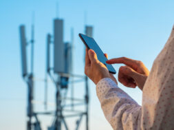 5G communications tower with man using mobile phone