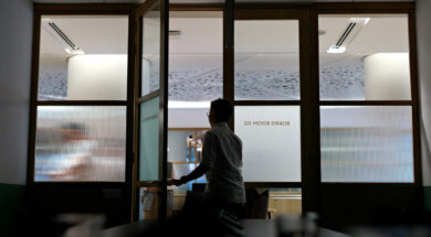 A group of Asian colleagues is leaving the boardroom after a meeting discussion, with the meeting room lights turned off.