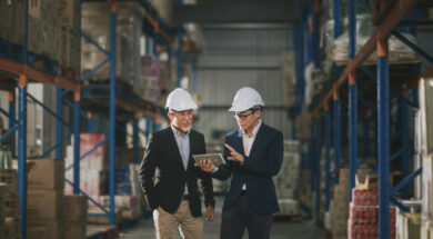 asian chinese management having discussion at warehouse with white hardhat using digital tablet