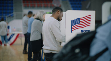 Elderly male voter with bulletin in hands comes to voting booth