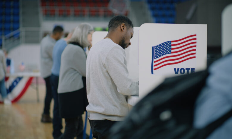 Elderly male voter with bulletin in hands comes to voting booth