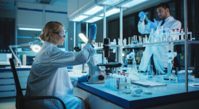 Female Medical Research Scientist Looks at Biological Samples Before Analysing it Under Digital Microscope in Applied Science Laboratory. Lab Engineer in White Coat Working on Vaccine and Medicine.