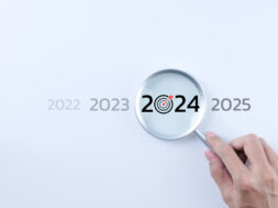 The 2024 new year business goals concept. A person holding a magnifying glass looking at the word year 2024 on white background. Business plan target strategy, Marketing trend 2024, Work focus,