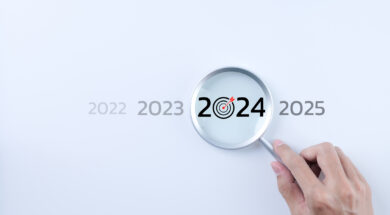 The 2024 new year business goals concept. A person holding a magnifying glass looking at the word year 2024 on white background. Business plan target strategy, Marketing trend 2024, Work focus,