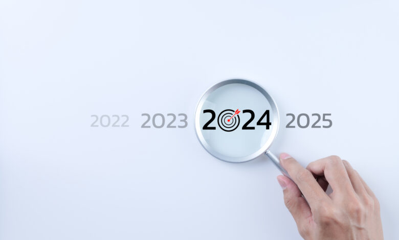 The 2024 new year business goals concept. A person holding a magnifying glass looking at the word year 2024 on white background. Business plan target strategy, Marketing trend 2024, Work focus,