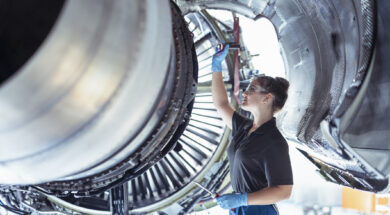 Female apprentice aircraft maintenance engineer work underneath jet engine