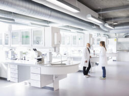 Two scientists in conversation, standing in laboratory