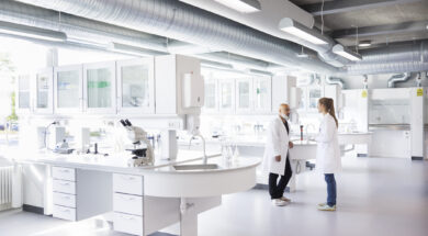 Two scientists in conversation, standing in laboratory