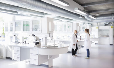 Two scientists in conversation, standing in laboratory