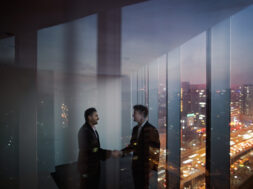 Businessmen shaking hands in office at night