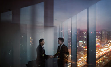 Businessmen shaking hands in office at night