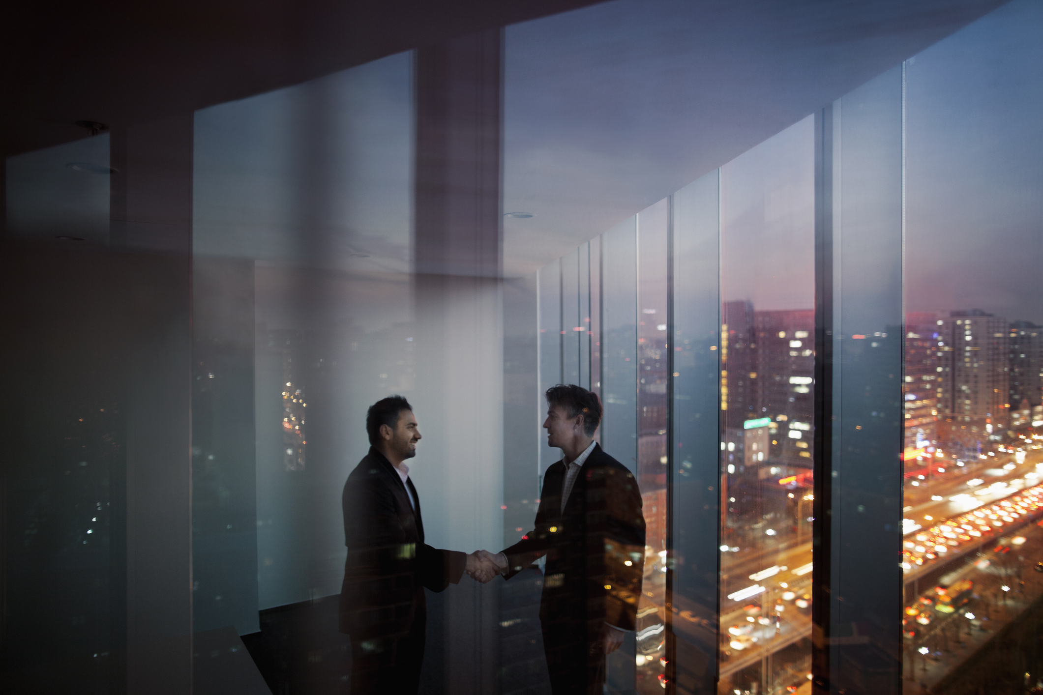 Businessmen shaking hands in office at night