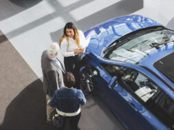 High angle view of saleswoman showing car to customers at showroom