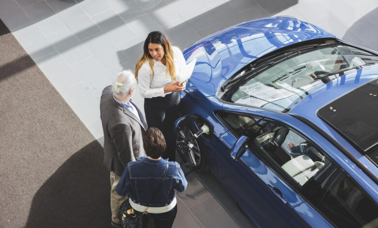 High angle view of saleswoman showing car to customers at showroom