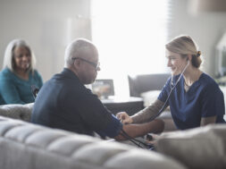 Nurse taking patient blood pressure in living room