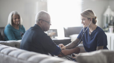 Nurse taking patient blood pressure in living room