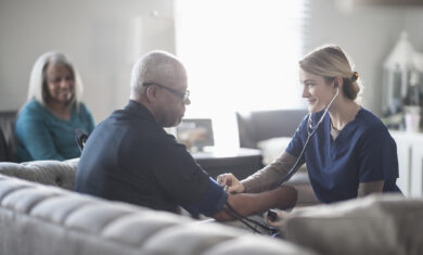 Nurse taking patient blood pressure in living room