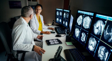 Doctors Sitting At Computer Desk Talking About Patient’s CT Scans