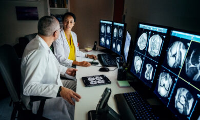 Doctors Sitting At Computer Desk Talking About Patient’s CT Scans