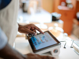Accurate, Real-time Data and Faster Speed of Service Can Invest in a POS System in Your Store. Close-up of a male African-American cashier placing orders via a point of sale (POS) software at a cashier counter of a coffee shop.