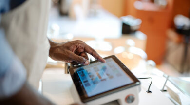 Accurate, Real-time Data and Faster Speed of Service Can Invest in a POS System in Your Store. Close-up of a male African-American cashier placing orders via a point of sale (POS) software at a cashier counter of a coffee shop.