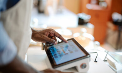 Accurate, Real-time Data and Faster Speed of Service Can Invest in a POS System in Your Store. Close-up of a male African-American cashier placing orders via a point of sale (POS) software at a cashier counter of a coffee shop.