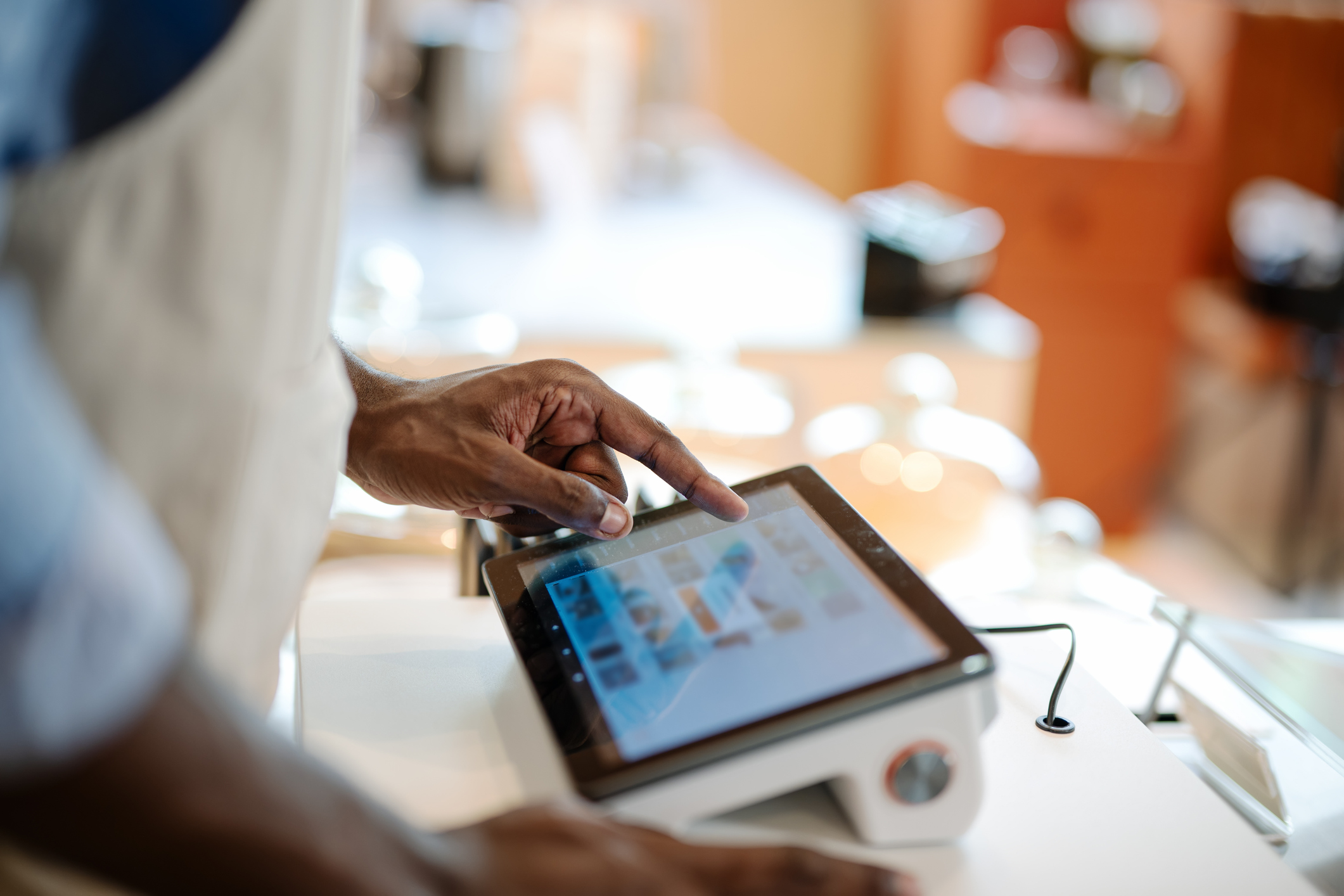 Accurate, Real-time Data and Faster Speed of Service Can Invest in a POS System in Your Store. Close-up of a male African-American cashier placing orders via a point of sale (POS) software at a cashier counter of a coffee shop.