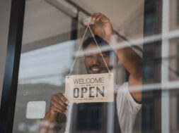 Young Asia coffee shop owner business man in apron with open sign at door shop.