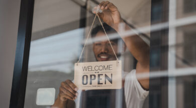 Young Asia coffee shop owner business man in apron with open sign at door shop.