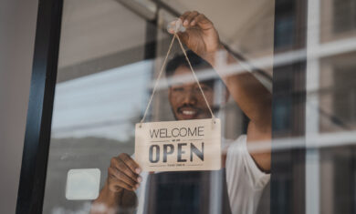Young Asia coffee shop owner business man in apron with open sign at door shop.