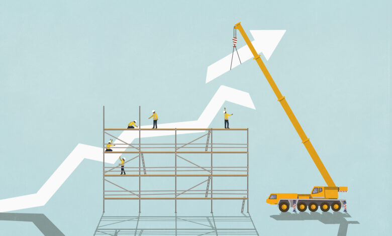 Construction workers on scaffolding below crane assembling ascending graph arrow