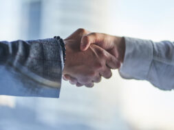 Hands on a business meeting. Two hands: a man in a jacket with a bracelet and a man in a white shirt are shaking each other. Handshake, the concept of a business arrangement with copy space.