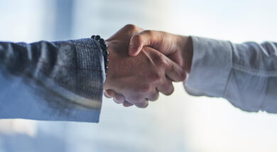 Hands on a business meeting. Two hands: a man in a jacket with a bracelet and a man in a white shirt are shaking each other. Handshake, the concept of a business arrangement with copy space.