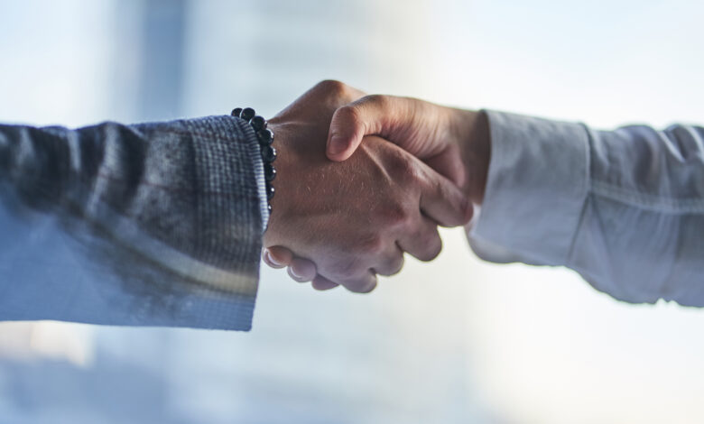 Hands on a business meeting. Two hands: a man in a jacket with a bracelet and a man in a white shirt are shaking each other. Handshake, the concept of a business arrangement with copy space.