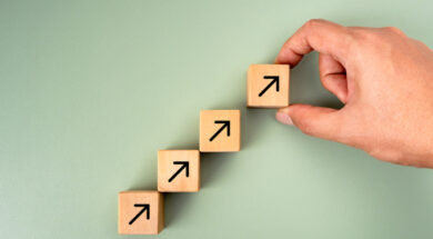 Business goal growth management, new objective, success plan, leadership concepts. Businessman hand arranged wooden cube blocks with rising arrow icon isolated on green background, minimalist style.