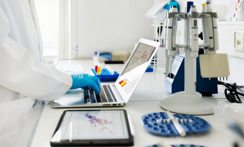 Close-Up Shot of Scientists Hands typing Data in Laptop in Laboratory