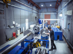 Gun technician extracting compression piston from large two stage gas gun in nuclear fusion research facility