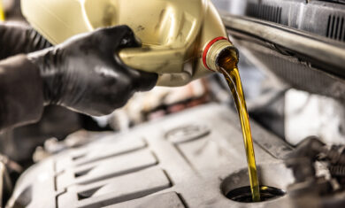 Mecanic pouring oil to car engine. Fresh motor oil poured during an oil change to a car