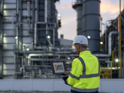 Dedicated engineer working until the late hours in the oil and gas industry with laptop.