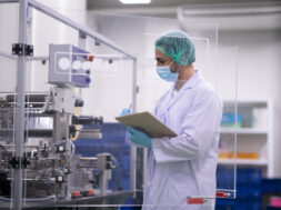 Laboratory technician inspecting pharmaceutical manufacturing in contaminate controlled room