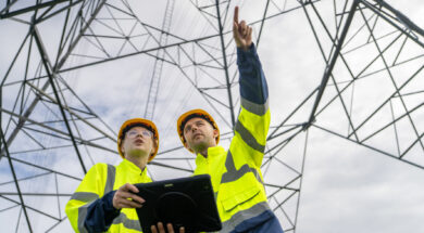 Electrical engineers inspecting high voltage power lines using digital tablet
