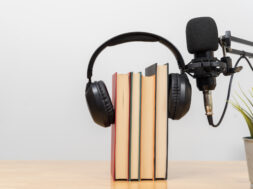 Headphones on books with microphone on desk symbolizing audiobook, podcast, learning and modern education