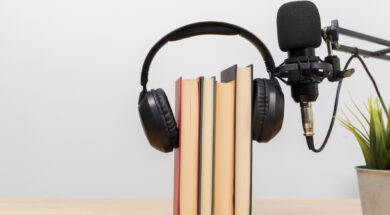 Headphones on books with microphone on desk symbolizing audiobook, podcast, learning and modern education
